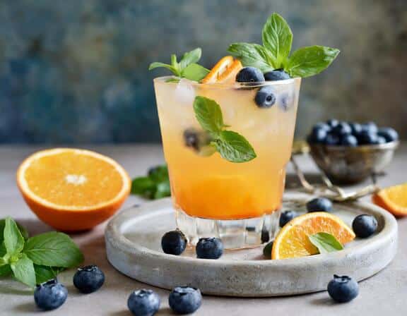 tangerine marigold mocktail with blueberries and basil as garnish