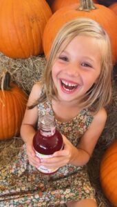 little girl enjoying kombucha in pumpkin patch